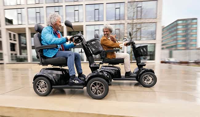 Deux hommes sur un scooter électrique 4 roues Life Mobility Presto S font la course